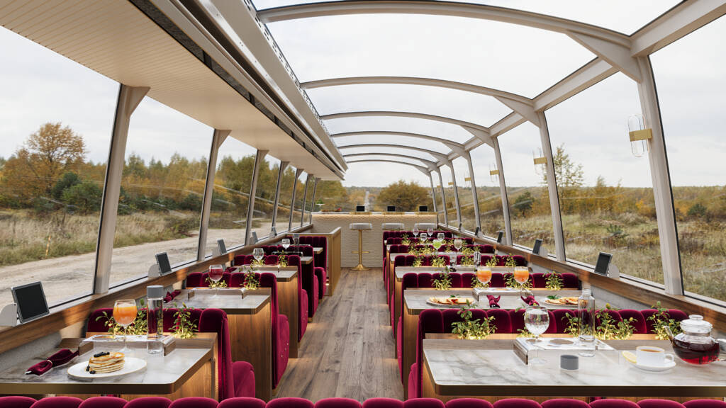 Interior of a Luxe Lounge Bus with a long table and chairs, showcasing plush seating and natural light for a sophisticated vibe.
